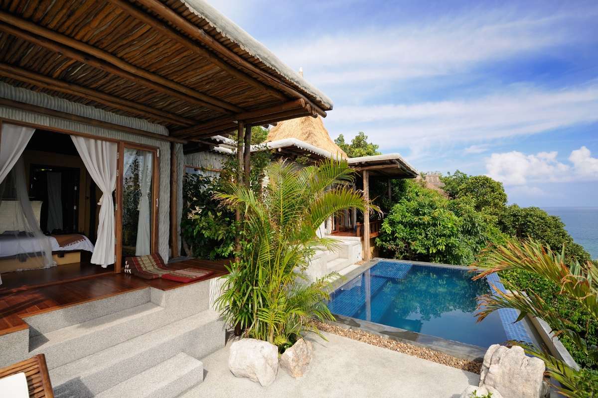 Tropical luxury villa with thatched roof, open-air design, private infinity pool overlooking ocean