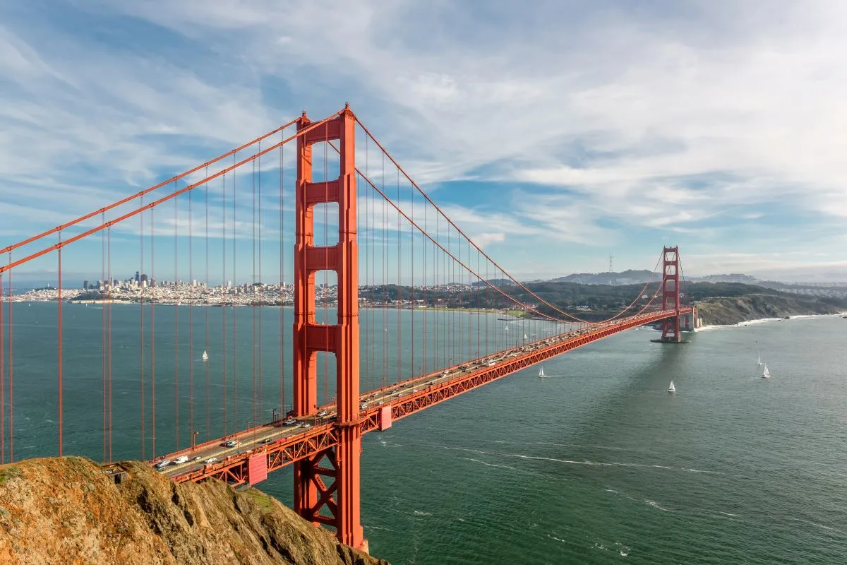 Golden Gate Bridge spanning San Francisco Bay on a clear day with sailboats in the water.