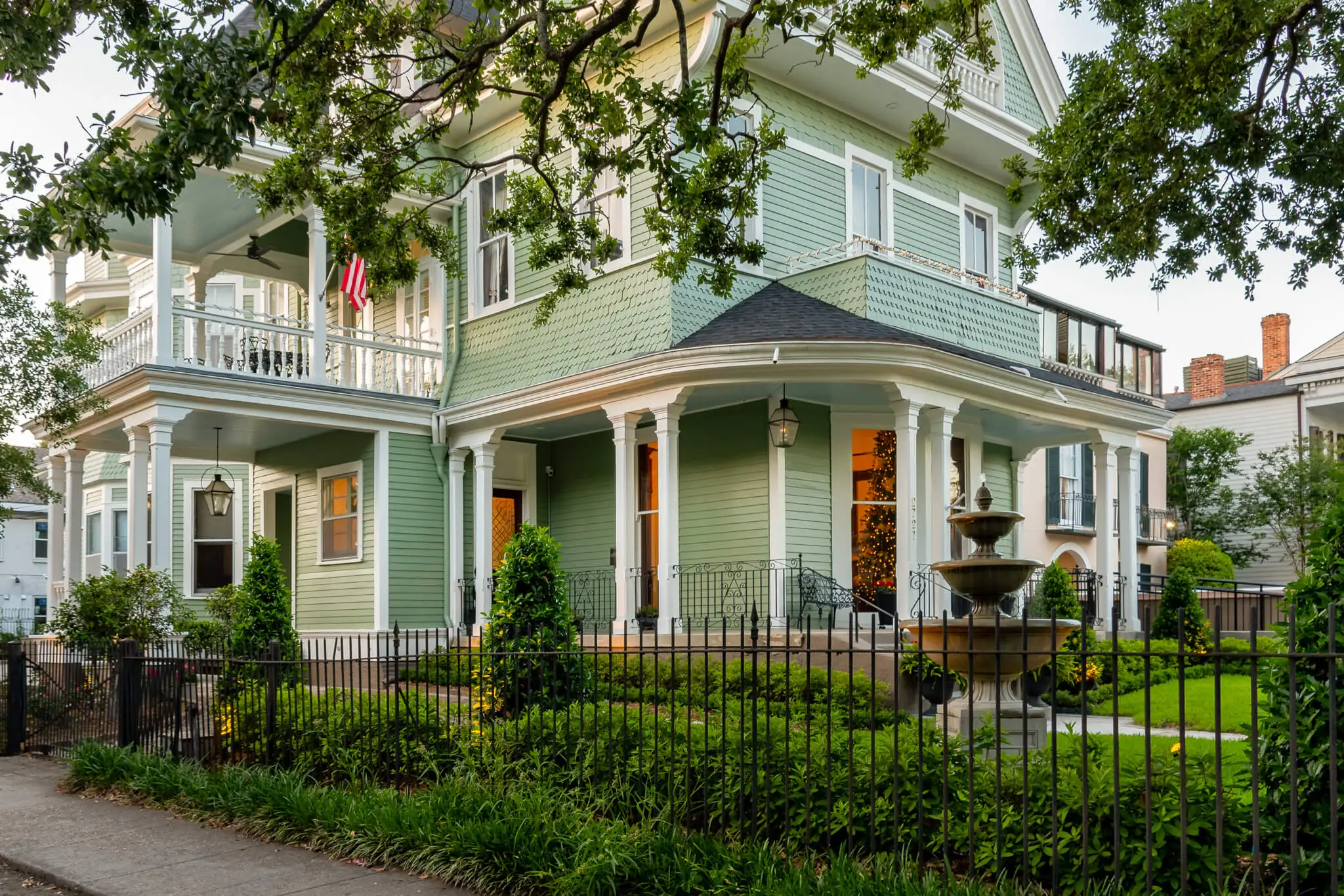 Front view of a grand Victorian villa showcasing ornate architectural details, large windows, decorative trim, and a spacious porch, surrounded by manicured gardens and mature trees.