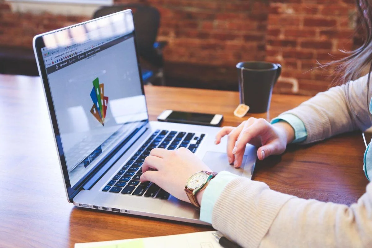 A person working on a laptop at a desk, representing how travel brands create and optimize digital content to improve visibility in AI-powered search results.