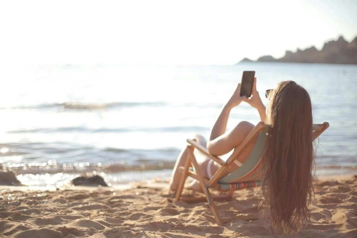Traveler using a laptop by the waterfront to research destinations using AI-powered search tools