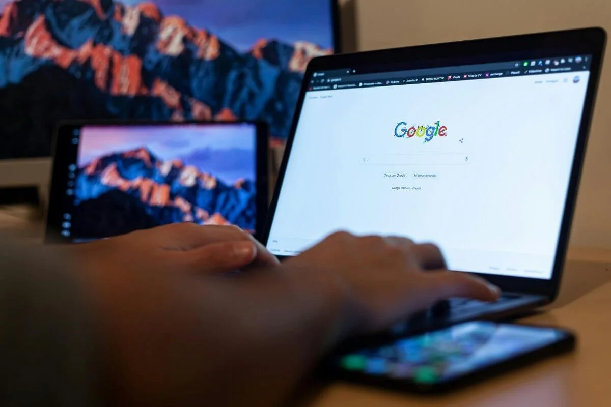 Person using a laptop, tablet, and smartphone to search on Google, illustrating modern multi-device search behavior