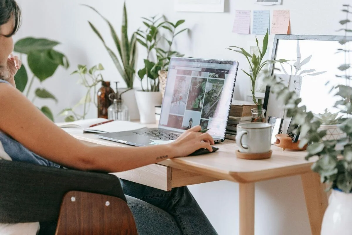 Person working at a home desk with a laptop, reviewing visual content and digital materials related to travel or tourism marketing.